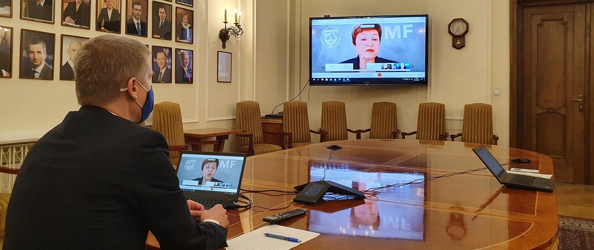 Wiceminister Piotr Nowak bierze udział w wideokonferencji. Wiceminister siedzi przy stole, przed nim komputer.
