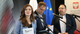 Minister Wanda Buk mówi do mikrofonu. Panowie Rafał Pawlak i dr hab. Grzegorz Tatoń stoją obok