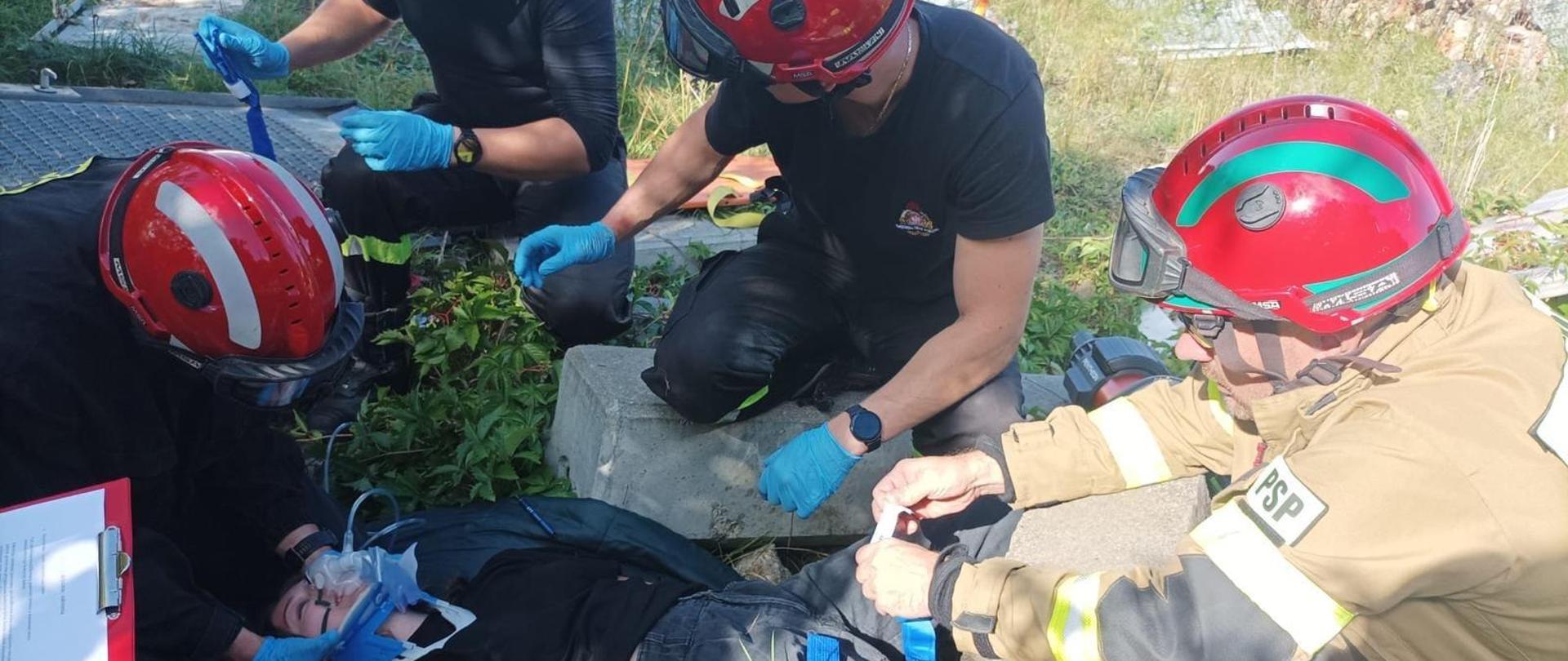 na zdjęciu strażacy w trakcie ćwiczenia, udzielający kwalifikowanej pierwszej pomocy poszkodowanej