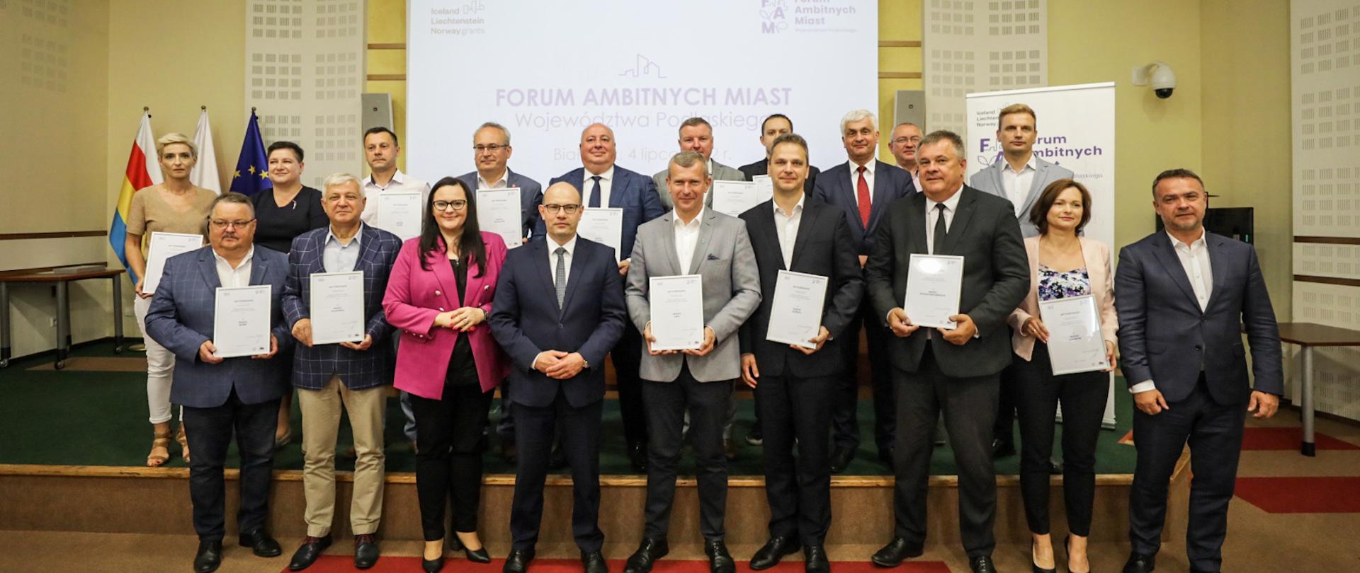 W sali konferencyjnej grupa osób stoi w dwóch rzędach i pozuje do zdjęcia. W pierwszym rzędzie wiceminister Małgorzata Jarosińska-Jedynak.