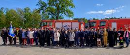 Zdjęcie przedstawia wszystkich uczestników uroczystości na tle samochodów pożarniczych.