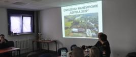 Uczestnicy narady – strażacy PSP w sali konferencyjnej oglądają prezentację z ćwiczeń.