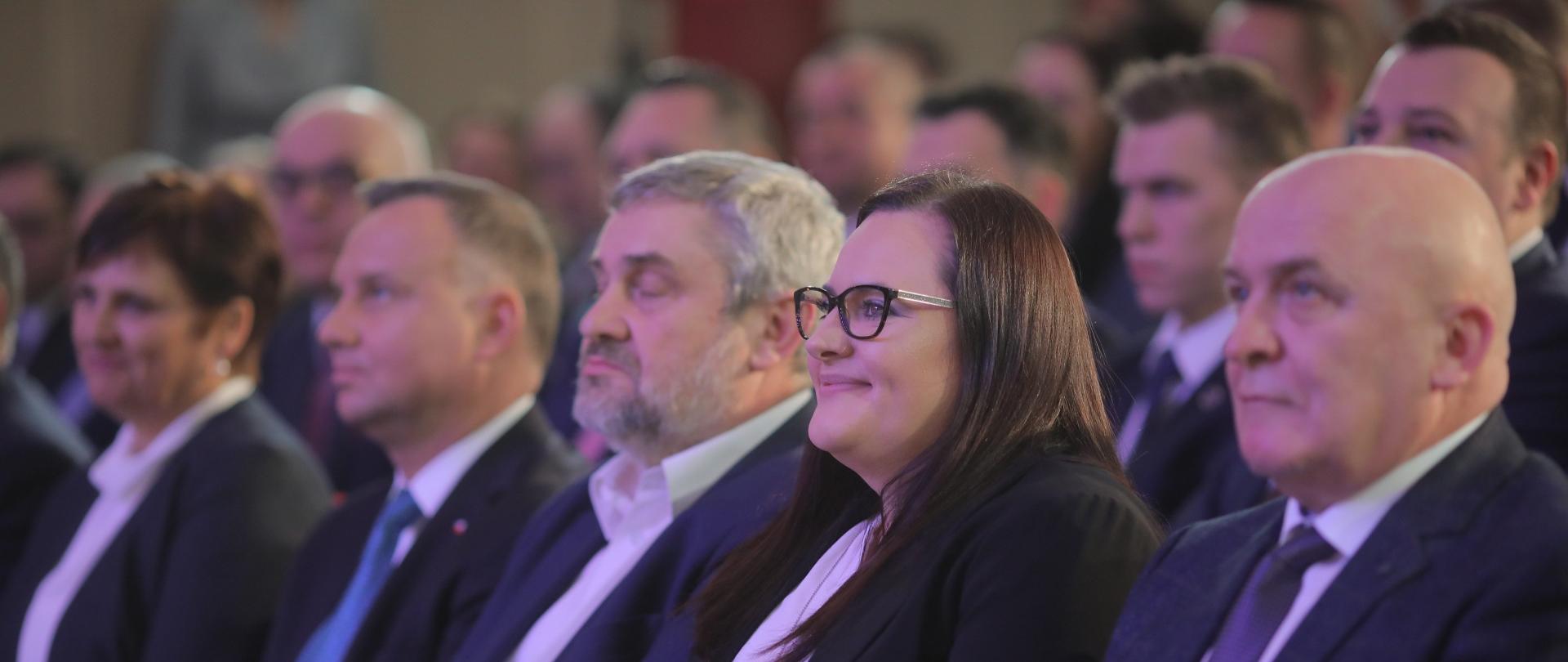 Na zdjęciu grupa osób siedząca w rzędach. W pierwszym rzędzie od lewej minister Jan Krzysztof Ardanowski, prezydent Andrzej Duda oraz minister funduszy i polityki regionalnej Małgorzata Jarosińska-Jedynak.