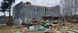 Zdjęcie przedstawia budynek mieszkalny z zerwanym dachem, który opadł przed budynkiem.