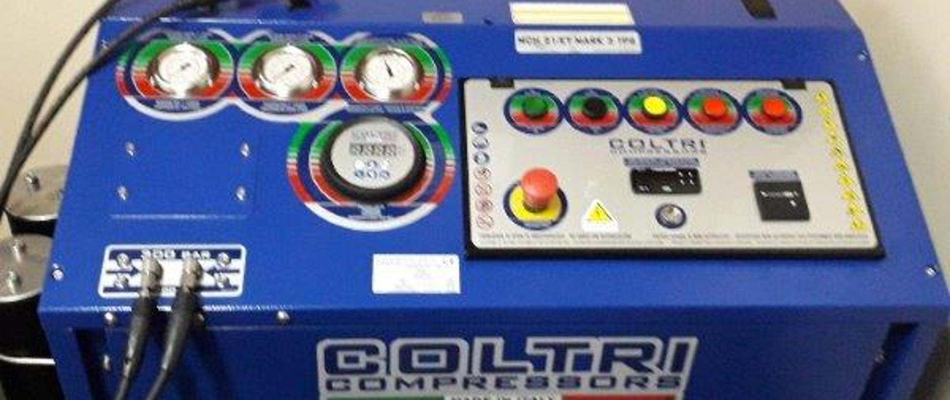 Na zdjęciu widzimy sprężarkę do ładowania butli koloru niebieskiego. Obudowa sprężarki wykonana z blachy o szerokości osiemdziesięciu centymetrów, głębokości siedemdziesięciu centymetrów oraz wysokości siedemdziesięciu centymetrów.
W przedniej części widzimy otwór wentylatora, w górnej części sprężarki uwidoczniony jest panel operatorski w skład którego wchodzą trzy zegary ( manometry) oraz sześć przycisków. Przód sprężarki oznaczony jest nazwą firmy "COLTRI", widzimy także dwa węże kolory czarnego wychodzące ze sprężarki zakończone specjalnymi reduktorami. 