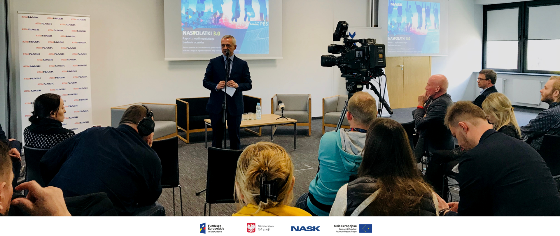 Minister Marek Zagórski podsumowuje debatę nt. raportu z badania Nastolatki 3.0. Stoi przed mikrofonem, przed nim siedzą pozostali uczestnicy spotkania.