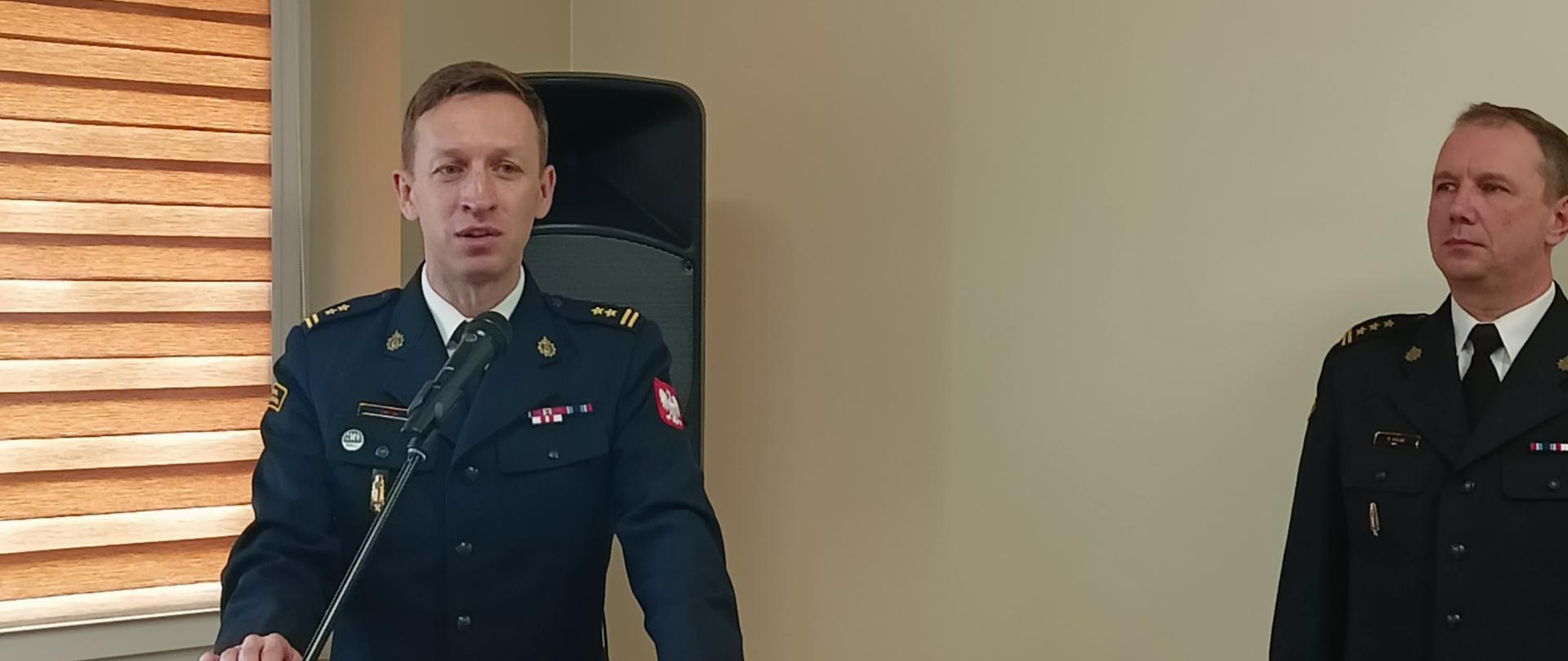 strażak przy mównicy, obok niego stoi drugi strażak