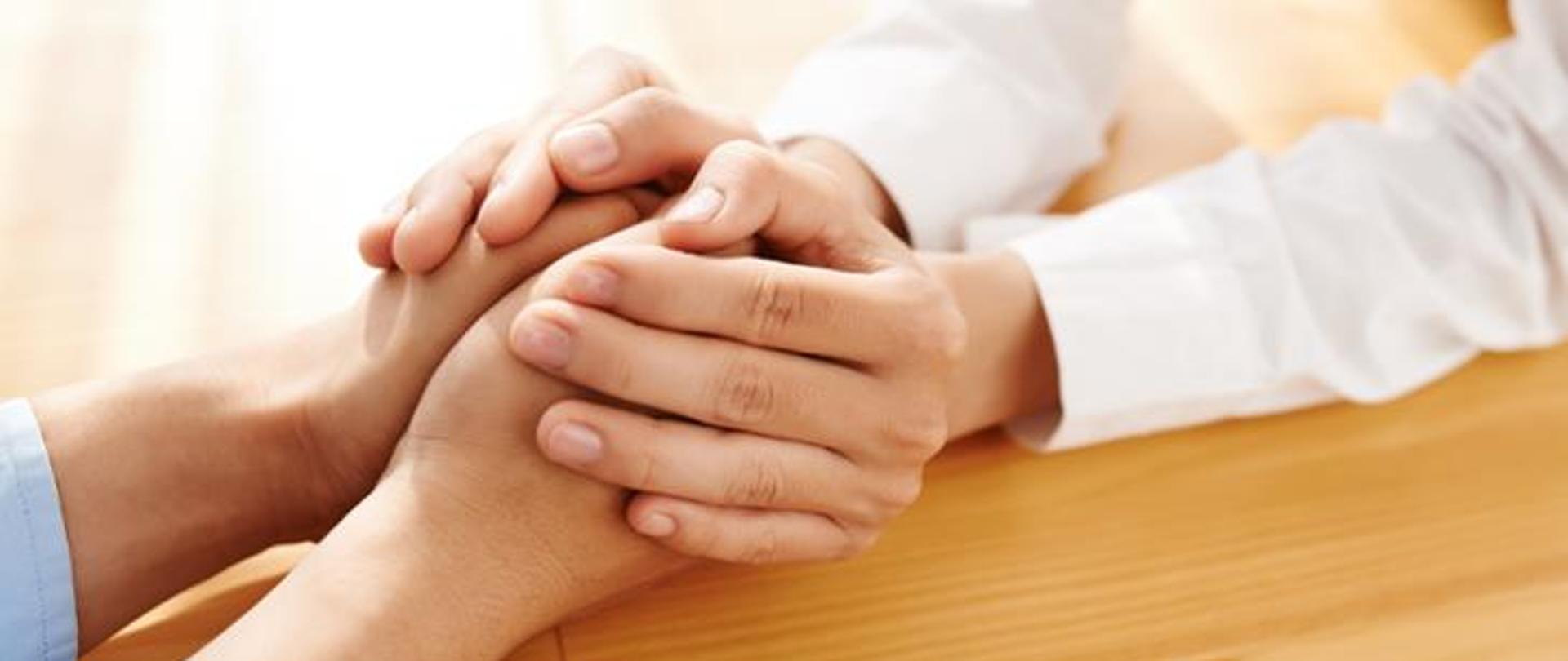 Ręce splecione w geście wsparcia