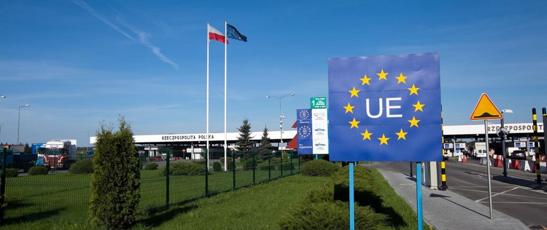 Przejście graniczne, tablica z symbolem UE, flagi Rzeczypospolitej Polskiej i Unii Europejskiej. 
