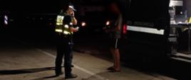 Inspektor podlaskiej Inspekcji Transportu Drogowego i funkcjonariusz Policji stoją koło nietrzeźwego kierowcy ciężarówki. Za kontrolowanym mężczyzną stoi oznakowany furgon ITD.