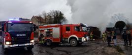 Strażacy dogaszają pożar. Na pierwszym planie widoczne dwa samochody strażackie (średni i ciężki samochodów ratowniczo gaśniczy).
