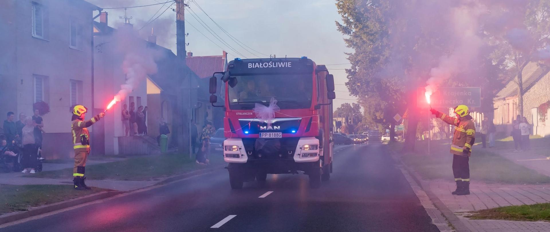 Na zdjęciu widnieją samochody wraz ze strażakami w trakcie ich oficjalnego przekazania. 