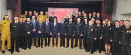 zdjęcie przedstawia grupę strażaków i samorządowców, w tle widoczna prezentacja