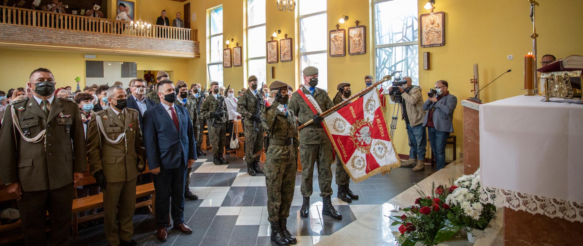 Żołnierze stoją w kościele i trzymają sztandar