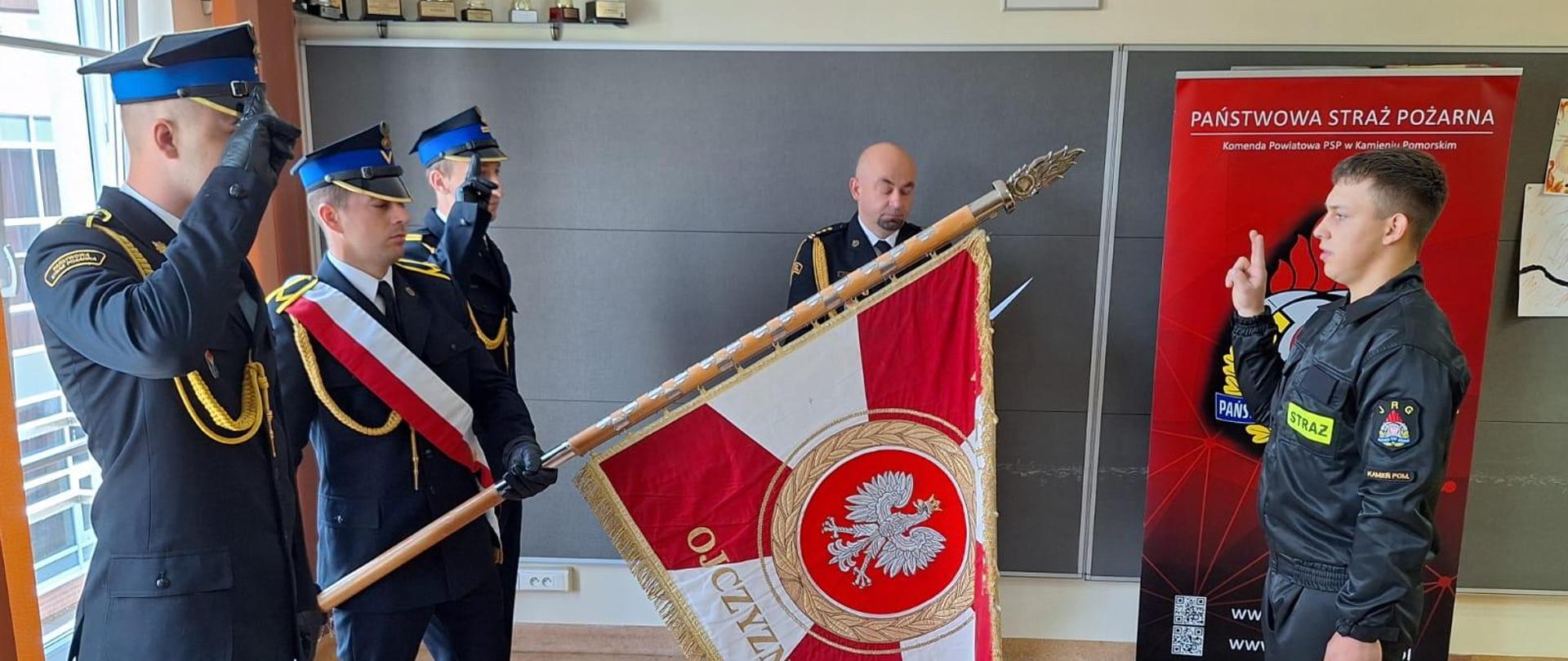 06.06.2024 roku tuż po godzinie 8:00 na świetlicy Komendy Powiatowej Państwowej Straży Pożarnej w Kamieniu Pomorskim odbyła się uroczysta zbiórka z okazji ślubowania nowo przyjętego funkcjonariusza do służby przygotowawczej w Państwowej Straży Pożarnej. Ślubowanie odbyło się na sztandar Komendy Powiatowej PSP w Kamieniu Pomorskim, które przyjął Komendant Powiatowy PSP st. bryg. Roman Pikulski.