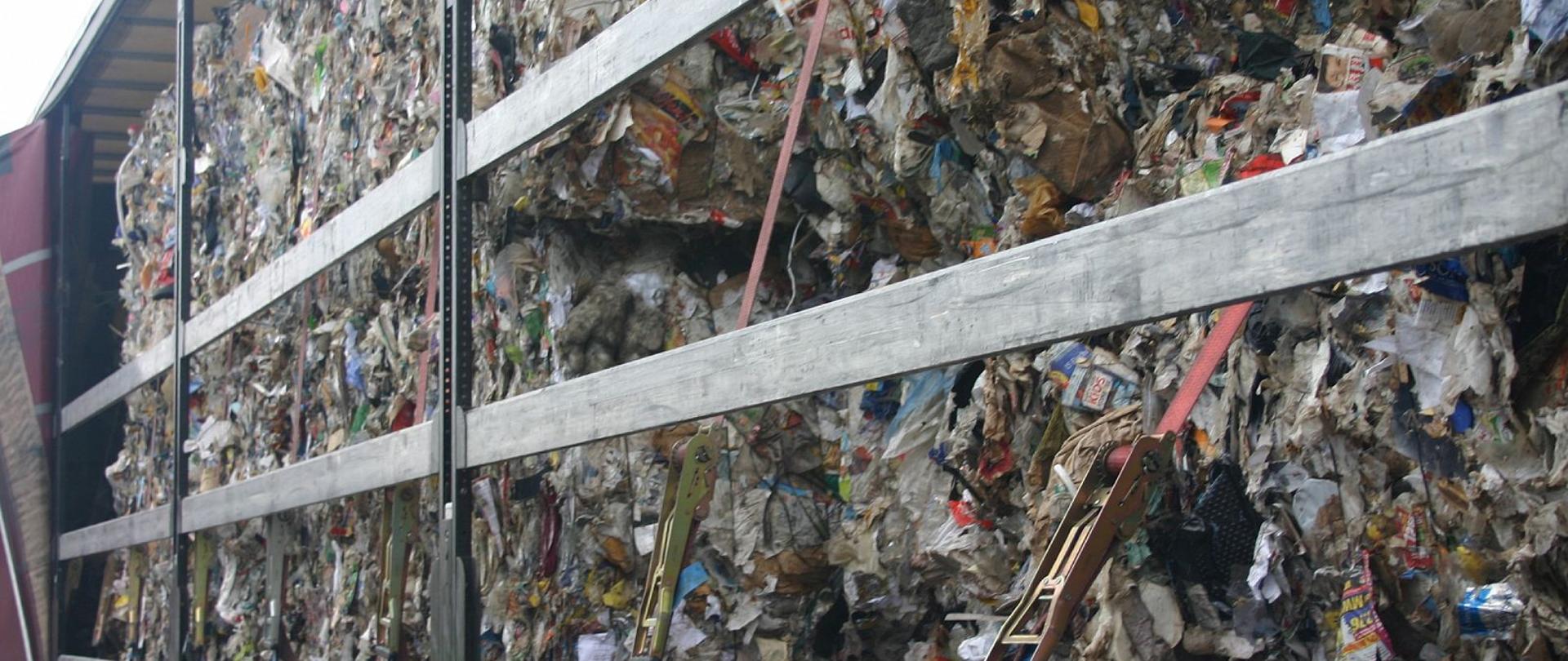 Otwarty bok naczepy, naczepa wypełniona sprasowanymi odpadami.