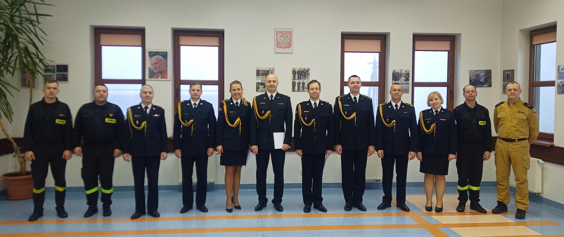 Zbiórka związana z wręczeniem awansów i nagród 12.12.2023 r. - wspólne zdjęcie w sali konferencyjnej komendy Komendant Powiatowy Państwowej Straży Pożarnej w Sokołowie Podlaskim wraz z strażakami w mundurach.
