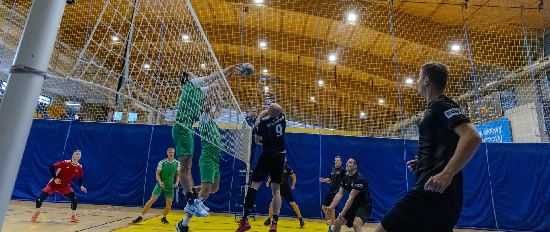 grupa osób grających w siatkówkeę na hali sportowej