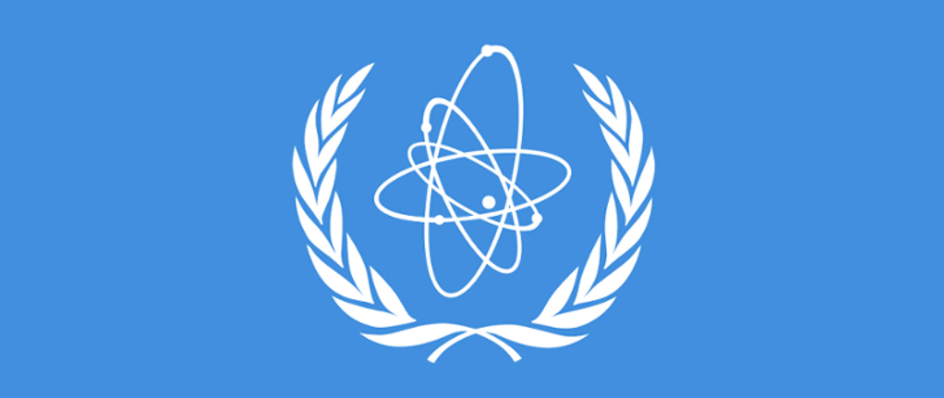 Godło MAEA - niebieskie tło, wieniec laurowy, trajektorie planet