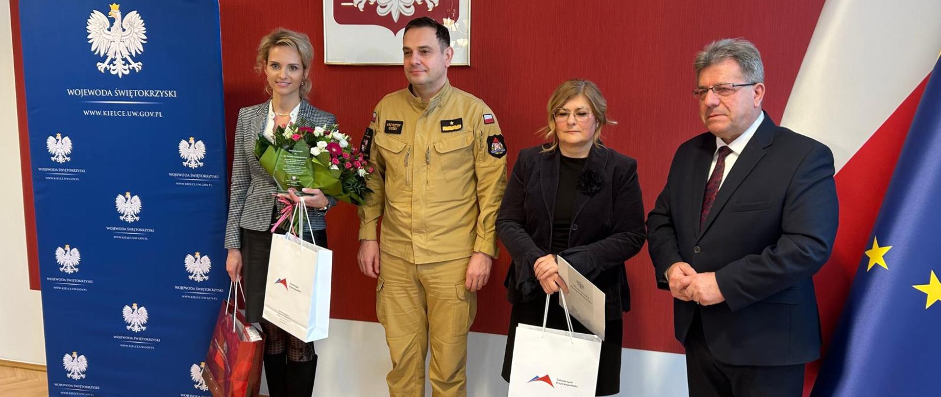 Na zdjęciu nagrodzone kobiety z wojewodą w garniturze oraz strażakiem w mundurze