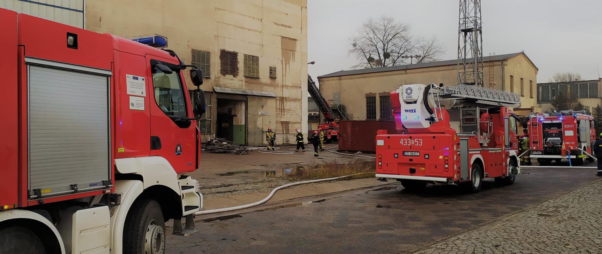 Pojazdy gaśnicze stoją przed budynkami w stoczni