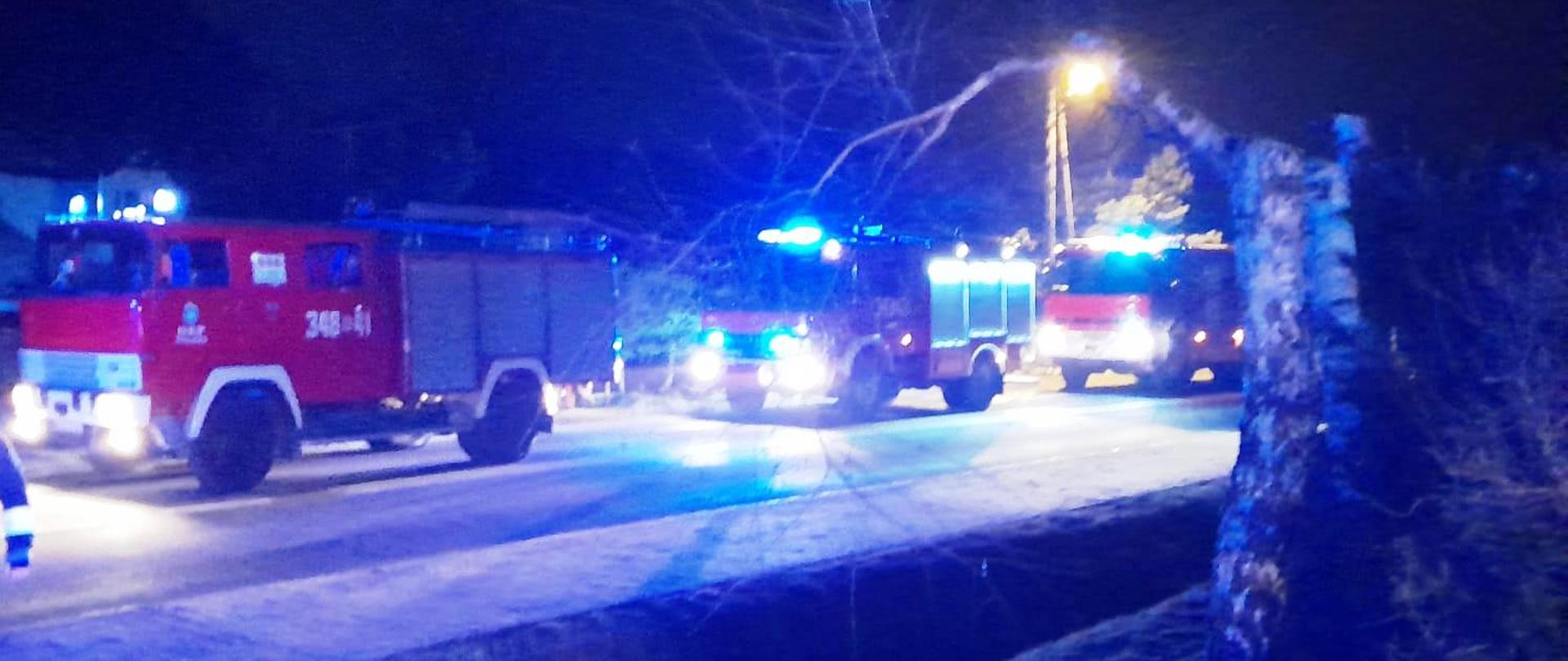 Samochody gaśnicze biorące udział w akcji stoją na drodze.