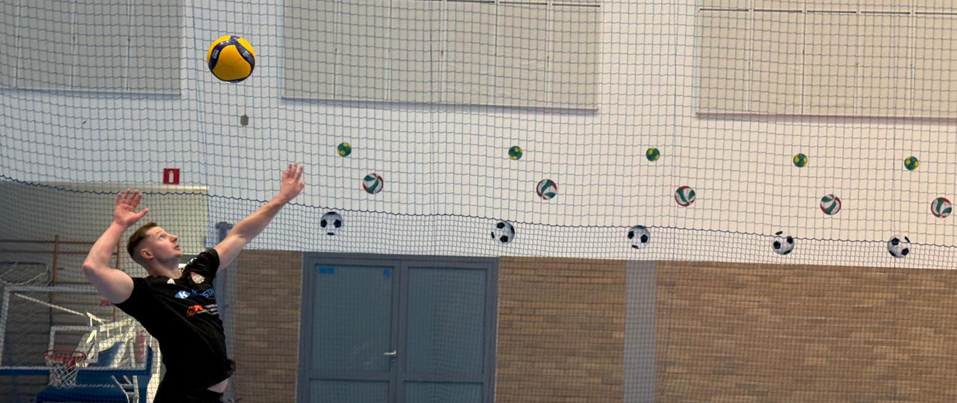 Strażak z KP PSP w Iławie wprowadza piłkę do gry wyskakując i serwując.