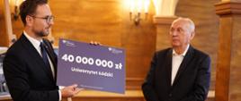 Minister Waldemar Buda przekazuje czek z rządowym wsparciem dla Uniwersytetu Łódzkiego