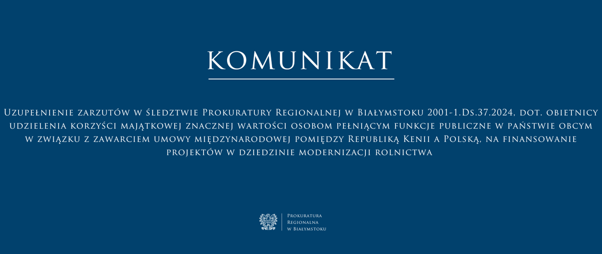 Baner ma ciemnoniebieskie tło i biały tekst, utrzymany w eleganckiej, klasycznej czcionce. W górnej części znajduje się duży napis „KOMUNIKAT” podkreślony cienką białą linią. Poniżej umieszczono treść komunikatu ” Uzupełnienie zarzutów w śledztwie Prokuratury Regionalnej w Białymstoku 2001-1.Ds.37.2024, dot. obietnicy udzielenia korzyści majątkowej znacznej wartości osobom pełniącym funkcje publiczne w państwie obcym w związku z zawarciem umowy międzynarodowej pomiędzy Republiką Kenii a Polską, na finansowanie projektów w dziedzinie modernizacji rolnictwa” Na dole, pośrodku, znajduje się logo Prokuratury Regionalnej w Białymstoku oraz jej nazwa.
