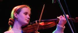 Zdjęcia przedstawia uczennicę klasy skrzypiec Maję Jóskowiak podczas występu na skrzypcach w trakcie koncertu świątecznego.
