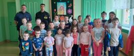 Zdjęcie przedstawia mundurowych w towarzystwie dzieci klasy trzeciej Szkoły Podstawowej podczas zajęć edukacyjnych 