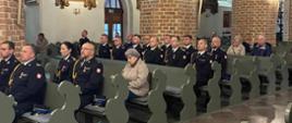 Na zdjęciu funkcjonariusze PSP na czele z kierownictwem KP PSP w Pucku uczestniczą w mszy świętej w Puckiej Farze. Są ubrani w stroje galowe ze złotymi sznurami na prawym ramieniu. 