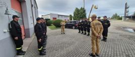 dwie zmiany służbowe w ubraniach koszarowych stoją naprzeciwko siebie podczas uroczystej zmiany służbowej, pomiędzy nimi stoją dowódca jednostki ratowniczo-gaśniczej oraz komendant powiatowy 