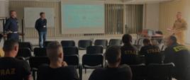 Zdjęcie przedstawia grupę strażaków, policjanta oraz pracownika z wojewódzkiego ośrodka ruchu drogowego w sali wykładowej podczas pogadanki.