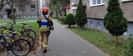 Zdjęcie przedstawia kierującego działaniem ratowniczym przy bloku wielorodzinnym.
