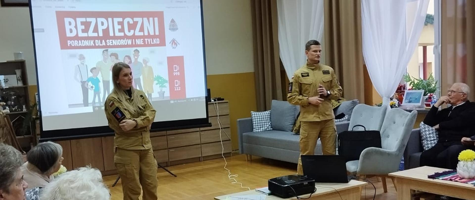 Strażacy pośród seniorów prowadza prelekcje w tle wyświetlana prezentacja 