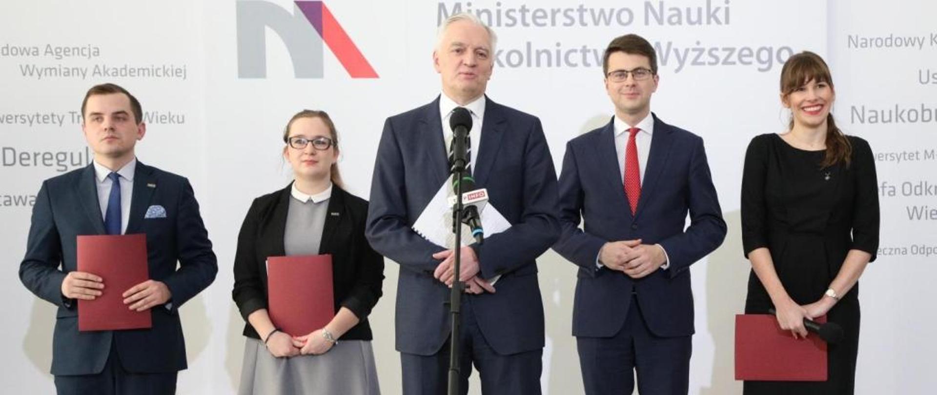 Studenci i ministrowie na tle ściany z logiem MNiSW