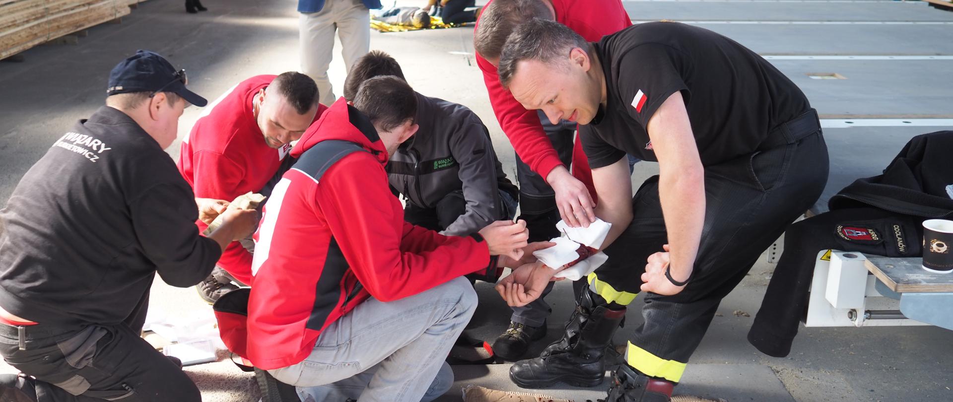 Pracownicy udzielają pierwszą pomoc poszkodowanemu.