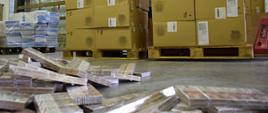 Pudełka z papierosami na podłodze, kartony z papierosami na paletach.