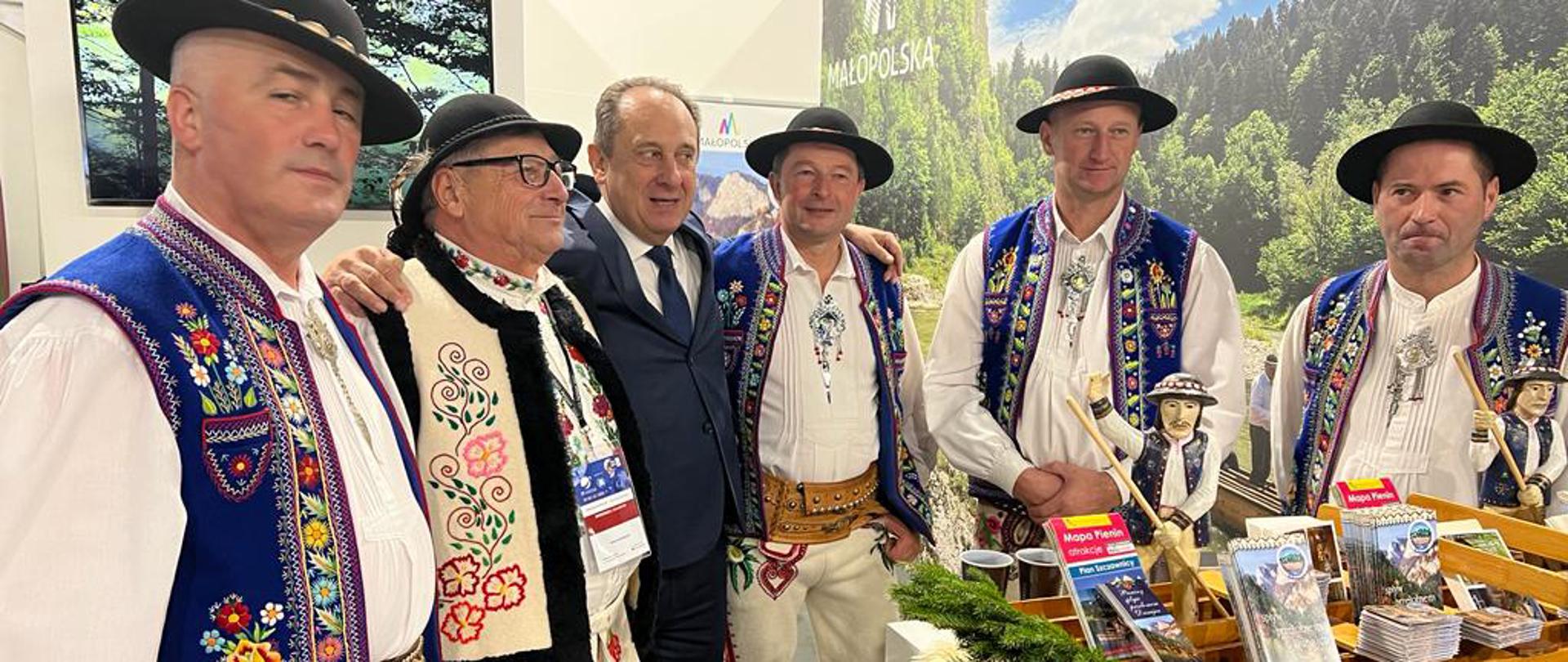 Sekretarz stanu Andrzej Gut-Mostowy na 28. Międzynarodowych Targach Turystycznych TT Warsaw - minister stoi w otoczeniu górali ubranych w tradycyjne ludowe stroje