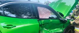 Zielony samochód marki Opel z uszkodzonymi przednimi drzwiami 