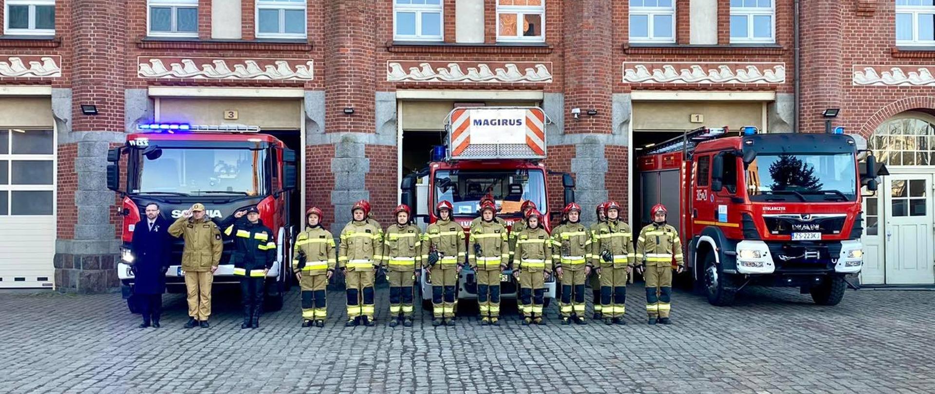 Po lewej stronie wojewoda zachodniopomorski Pan Zbigniew Bogucki wraz z zachodniopomorskim komendantem wojewódzkim st. bryg Jarosławem Tomczykiem psp oraz komendantem miejskim psp w Szczecinie. W centrum zdjęcia podział bojowy JRG5 w Szczecinie. Za nimi wystawione samochody na sygnałach świetlnych. Zdjęcie zrobione na tle Komendy Wojewódzkiej PSP w Szczecinie.