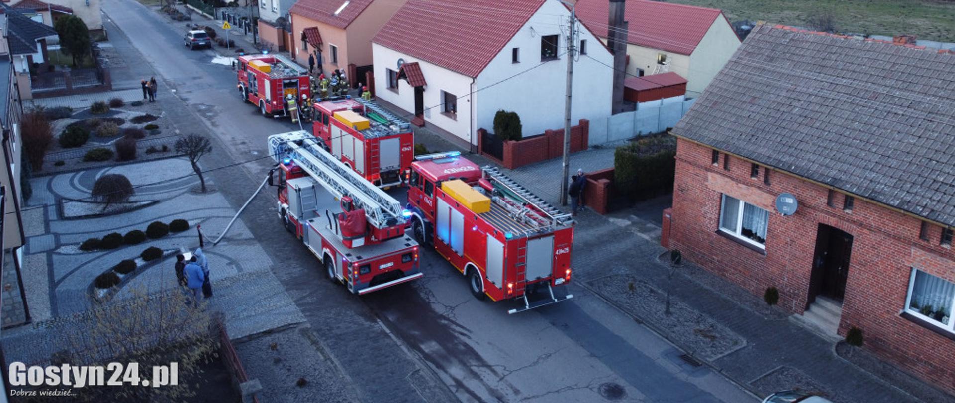 Zdjęcie przedstawia samochody pożarnicze stojące przy budynkach.