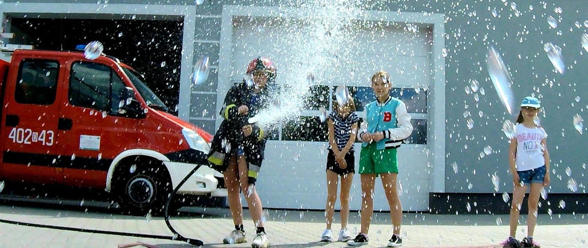 Grodkowska Gra Miejska - zdjęcie przedstawia uczestnika gry miejskiej podającego wodę z prądownicy wodnej