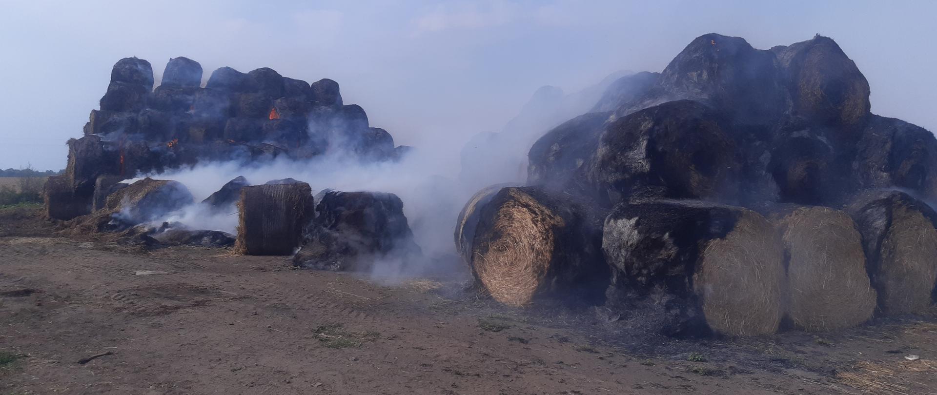 Palący się stóg siana na polu uprawnym.