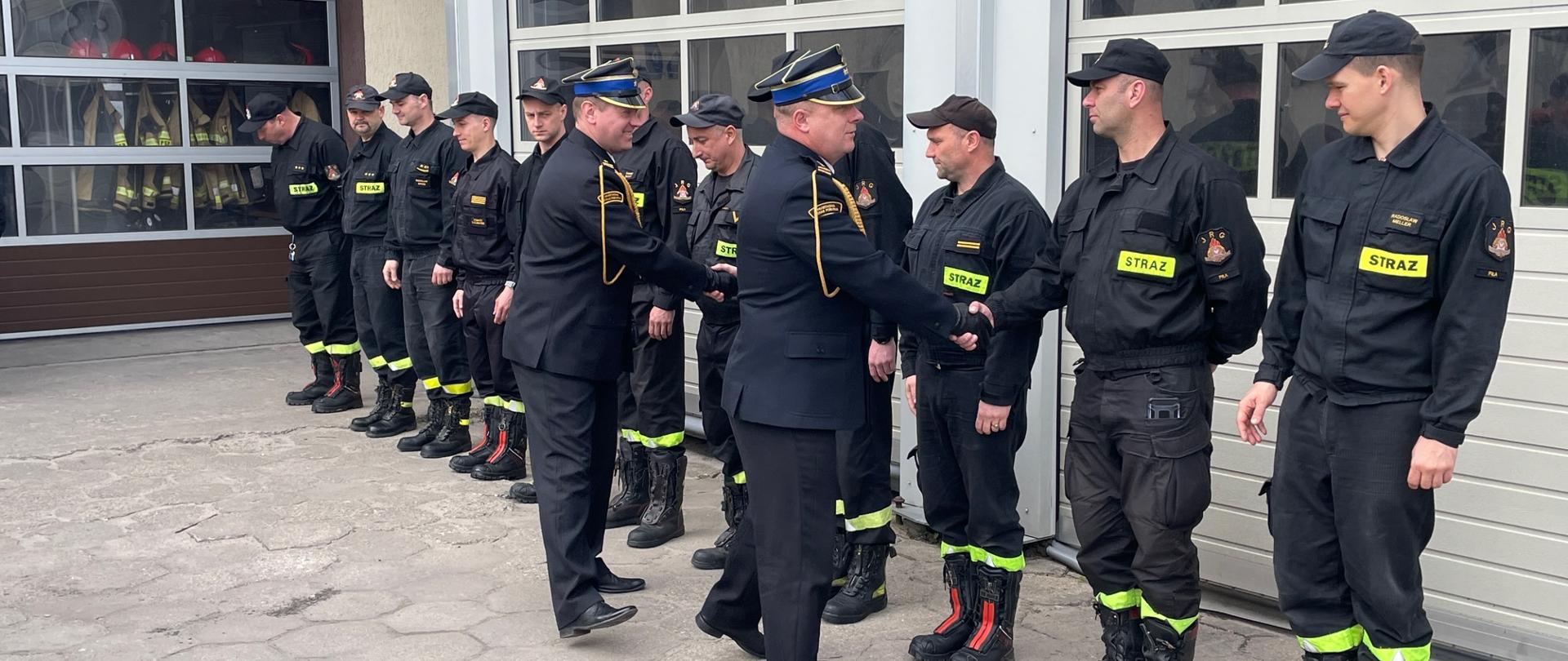 Na zdjęciu widać strażaków oraz Komendantów KP PSP w Pile podczas uroczystej zmiany służby z okazji Dnia Strażaka.