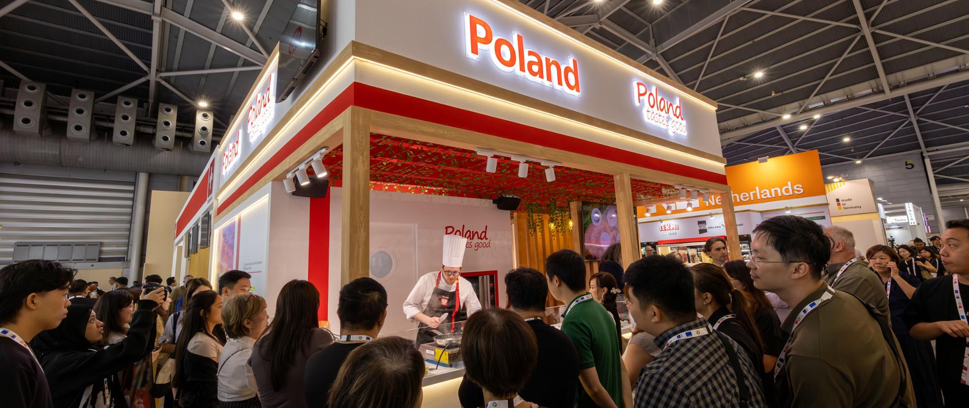 Polskie stoisko narodowe na targach w Singapurze - kucharz przygotowuje potrawy, na pierwszym planie odwiedzający targi