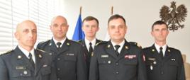 Czterech mężczyzn w mundurach strażackich pozuje do zdjęcia.