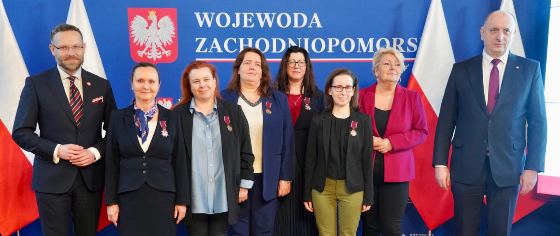 Grafika przedstawia zdjęcie grupowe osób odznaczonych za zasługi w walce z pandemią