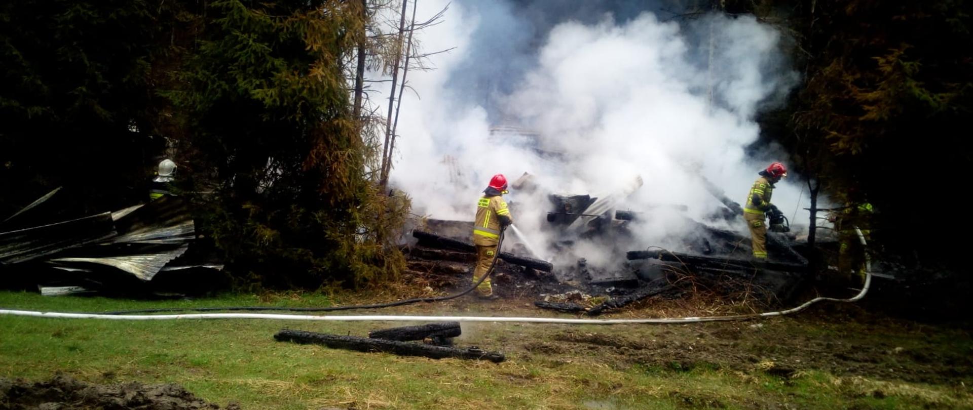 Zdjęcie przedstawia strażaków pracujących na pogorzelisku. 
